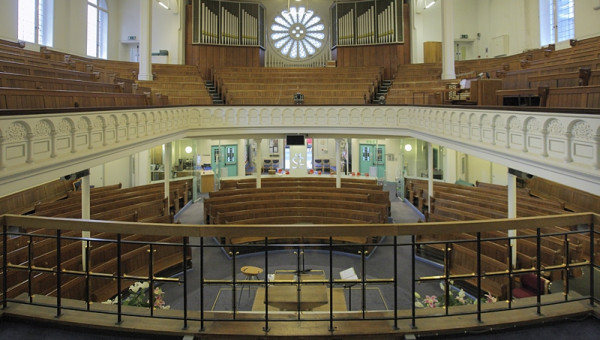 view of church from front looking at rose window pews and organ